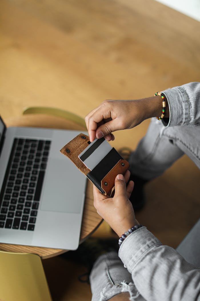 Close-up of hands using credit card near laptop for online payments.